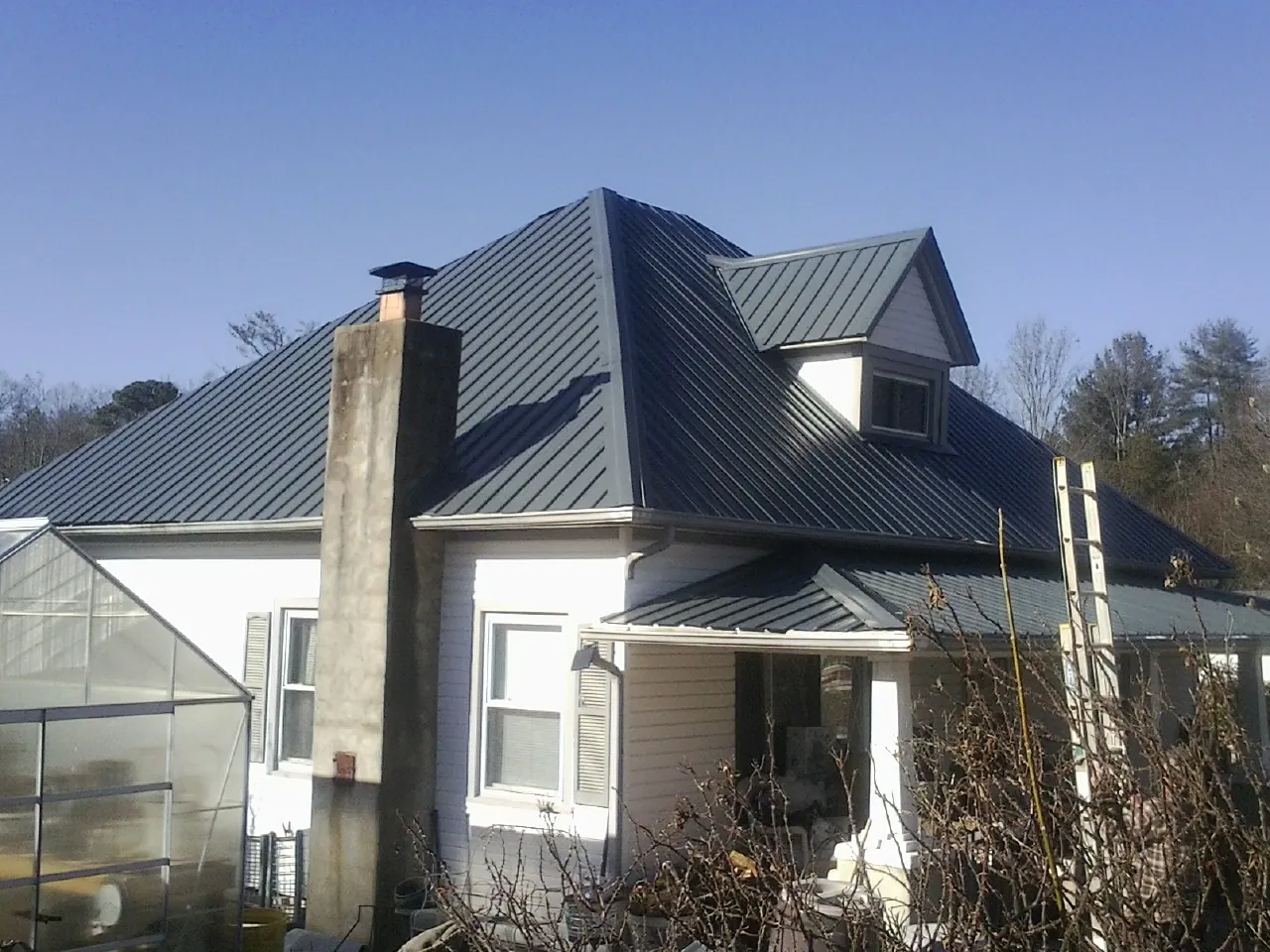 Dark blue standing seam metal roof on a white farmhouse with dormer — Slate & Tile Roof Repair by Roofing Brothers in Redmond