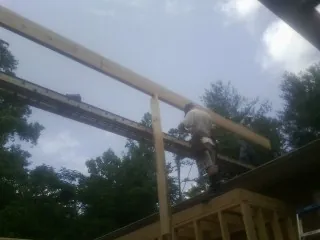 Carpenter setting a ridge beam over a new addition frame — Ice Dam Removal by Roofing Brothers in Redmond