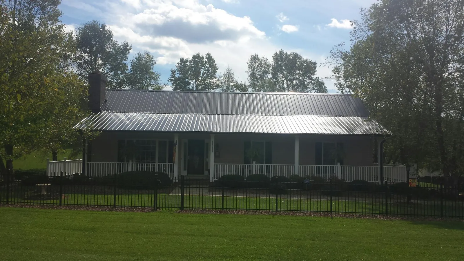 Gray metal roof on a brick ranch with a full width front porch — Gutter Guard Installation work by our crew in Redmond