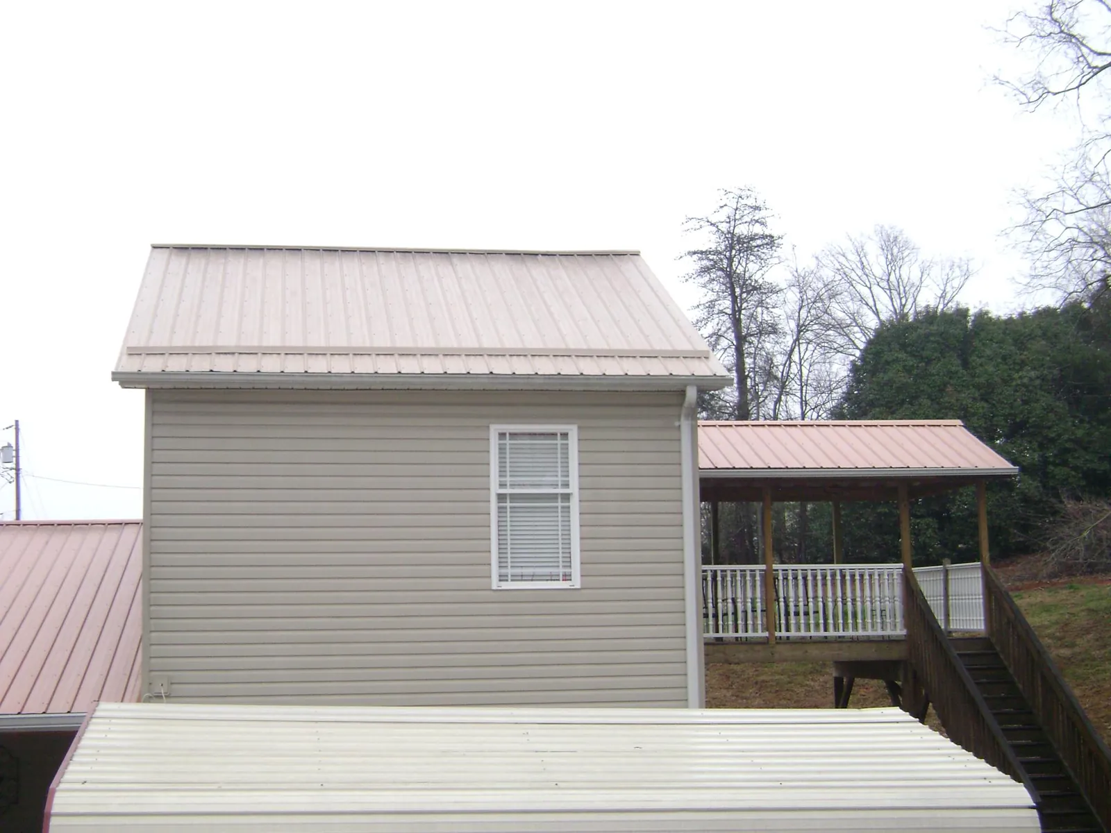Tan metal roofs on a two story addition and attached porch, from a Roof Replacement job in Redmond