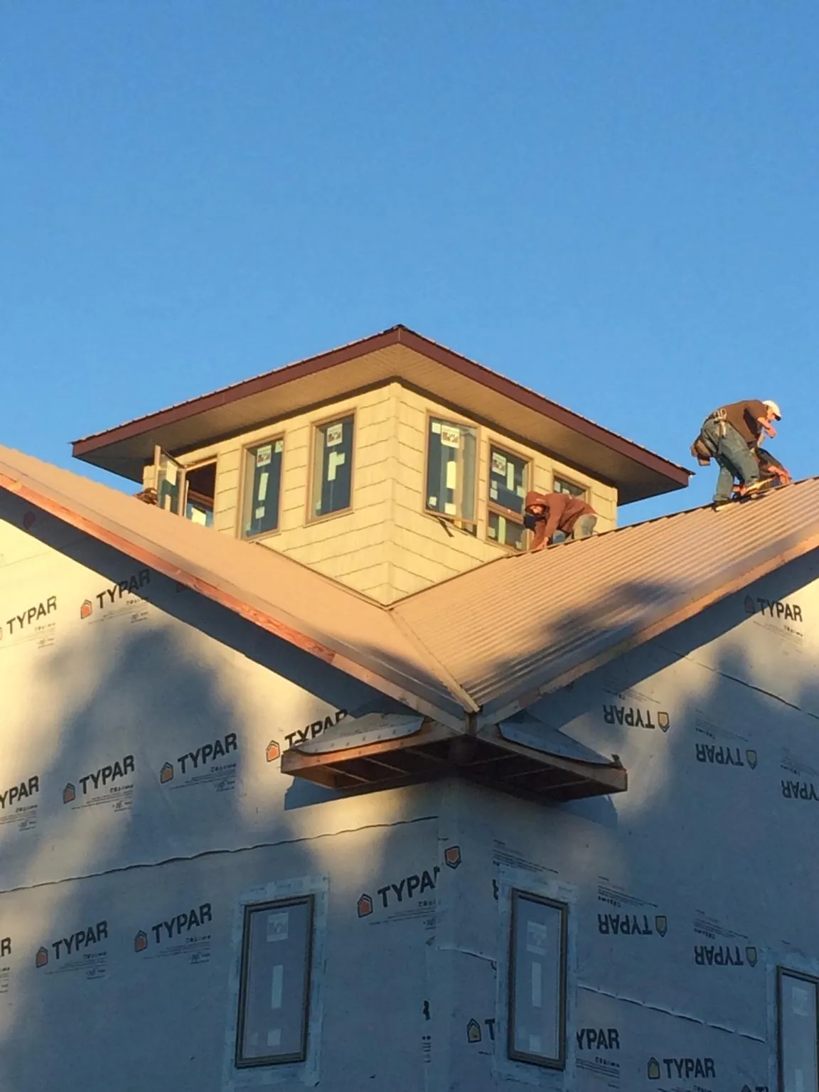 Roofers working around a rooftop cupola on a new metal roof at sunset — Roof Waterproofing in Redmond by Roofing Brothers